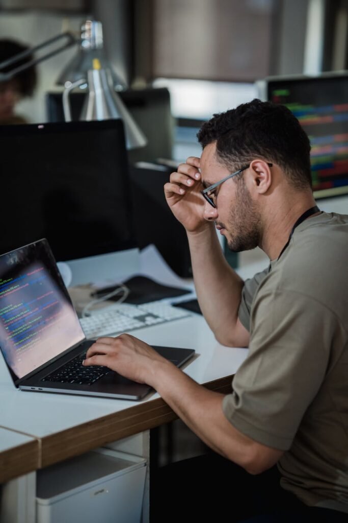 man thinking and typing on laptop